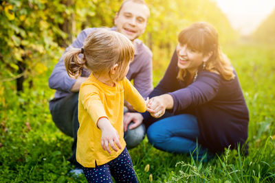 Side view of mother and daughter sitting on field