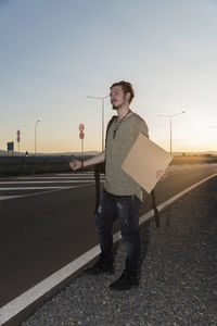 Man gesturing while standing on road against sky