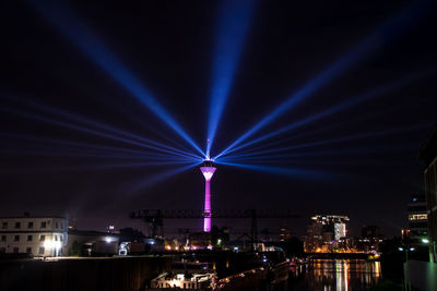 Illuminated city against blue sky at night