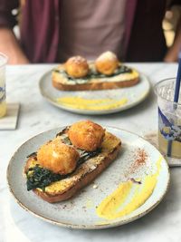 Close-up of hand holding food in plate on table