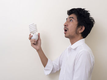 Portrait of young man standing against white background