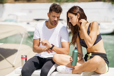 Couple checking time while sitting at harbor