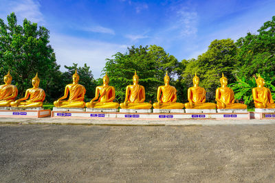 Gold colored statues against trees