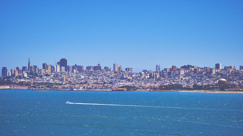 Scenic view of city next to sea against clear sky