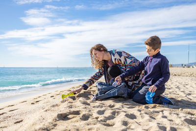 Mother and son picking plastic and garbage on the beach