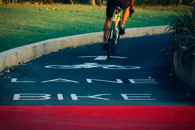 Low section of man riding bicycle on road