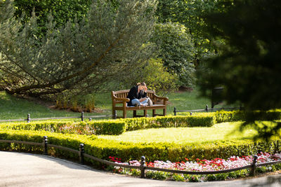 Attractive young woman reading book while sitting on grass in green public park. springtime outdoors