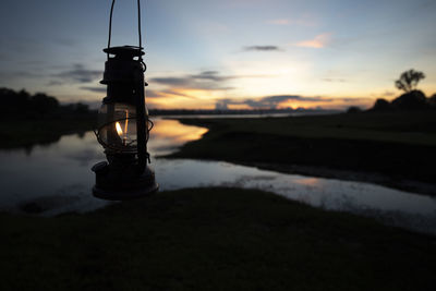 Silhouette tower by lake against sky at sunset