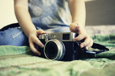 Midsection of girl holding camera on bed
