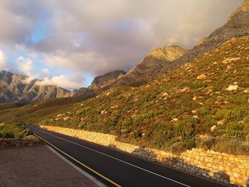 Road by mountains against sky