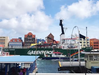 Boats in harbor by buildings against sky in city