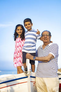 Grandfather with grandchildren on boat against sky