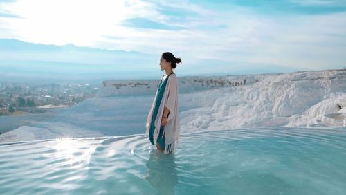 Woman standing in swimming pool against sea