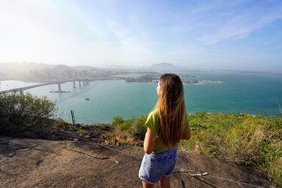 Woman admiring the landscape from lookout top view at sunset, vitoria, espirito santo, brazil