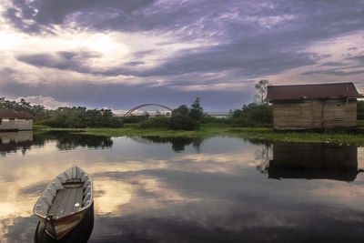 Boat on river against sky during sunset
