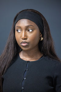 Portrait of young woman against black background