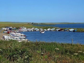 Boats in calm sea against clear sky