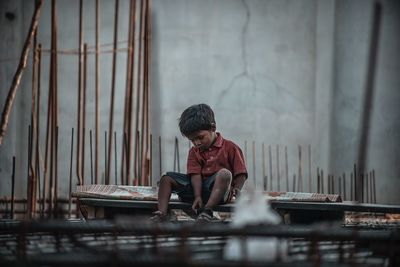 Full length of boy sitting on wall