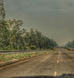 Road by trees against sky seen through windshield