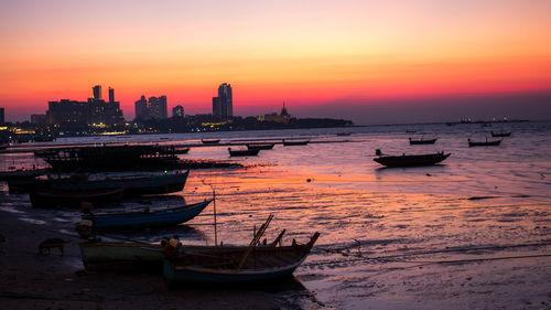 Boats moored in sea against sky during sunset