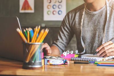 Midsection of man holding pencils on table