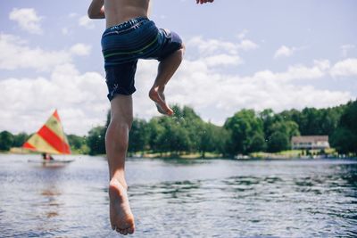 Low section of child on lake against sky