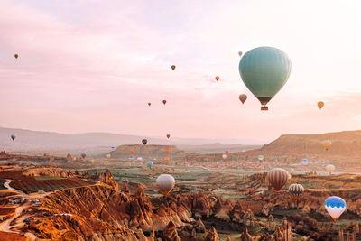 Hot air balloons flying over landscape against sky