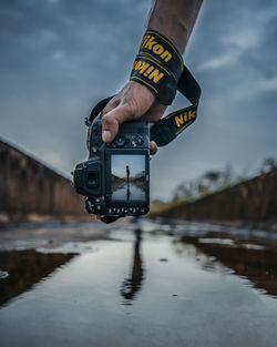 Man photographing at camera against sky