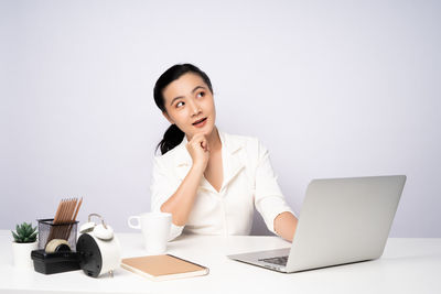 Young woman using mobile phone while sitting on table