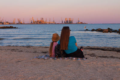 Girl staycation picnicking on sea sand beach with sunset background. local travel. evening seascape.