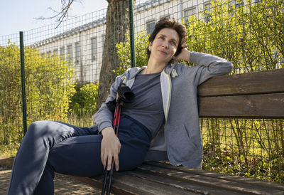 Portrait of young man sitting on bench in park