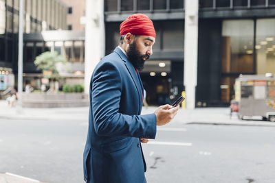 Indian businessman in manhattan using smartphone, walking in the street