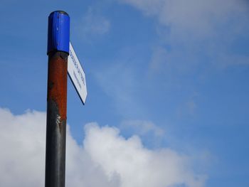 Low angle view of road sign against blue sky