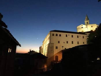 Silhouette buildings against clear sky at dusk