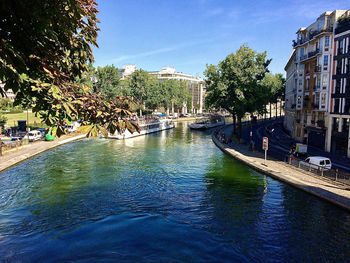 Canal amidst buildings in city against sky