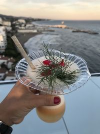 Close-up of hand holding drink against sea