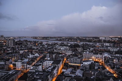 High angle view of illuminated city against cloudy sky