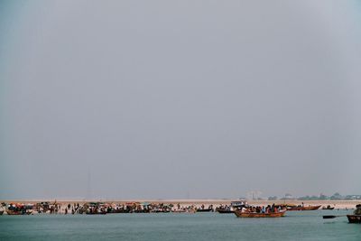 Boats sailing in sea against clear sky