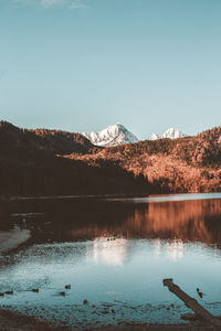 Scenic view of lake by mountains against clear sky