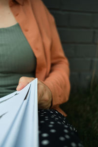 Young adult millennial reads book. lifestyle and body positive. green grass and brick wall. close up