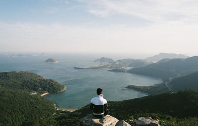 Rear view of man on sea shore against sky