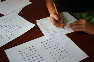 Midsection of boy writing on paper at home