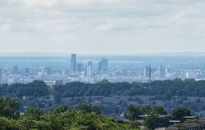 Trees and buildings in city against sky