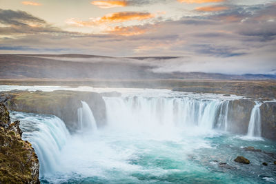 View of waterfall against cloudy sky