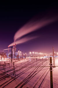 Smoke emitting from smoke stacks by railroad tracks at night