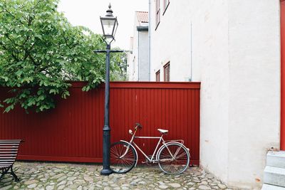 Bicycle by street against red wooden wall by white building