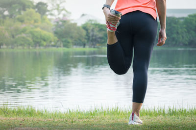 Low section of woman standing by lake