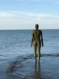 Statue in sea against sky