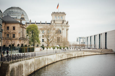 Spree river by reichstag building against sky