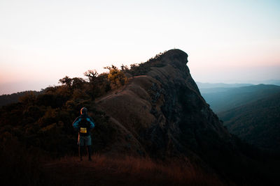 Rear view of man standing on mountain against sky